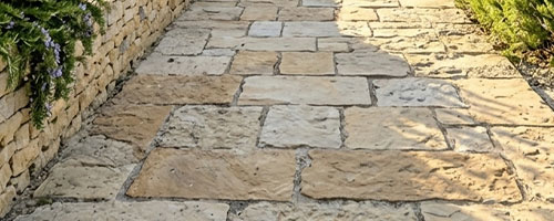 Continuité visuelle entre plage de piscine et terrasse couverte en travertin, bougainvillée sur pilier en pierre